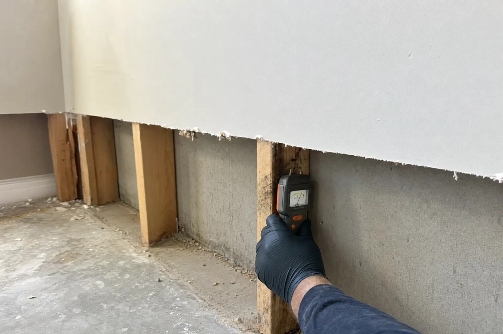Moisture meter checking a wet stud after drywall was cut away